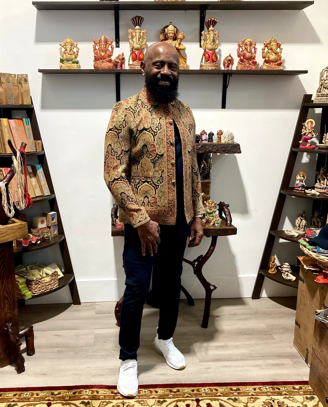 Smiling customer in an ornate paisley jacket inside the boutique